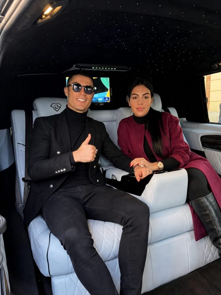 Cristiano Ronaldo and Georgina Rodriguez seated in the rear cabin of a luxury van with white quilted leather seats and a starlight headliner.