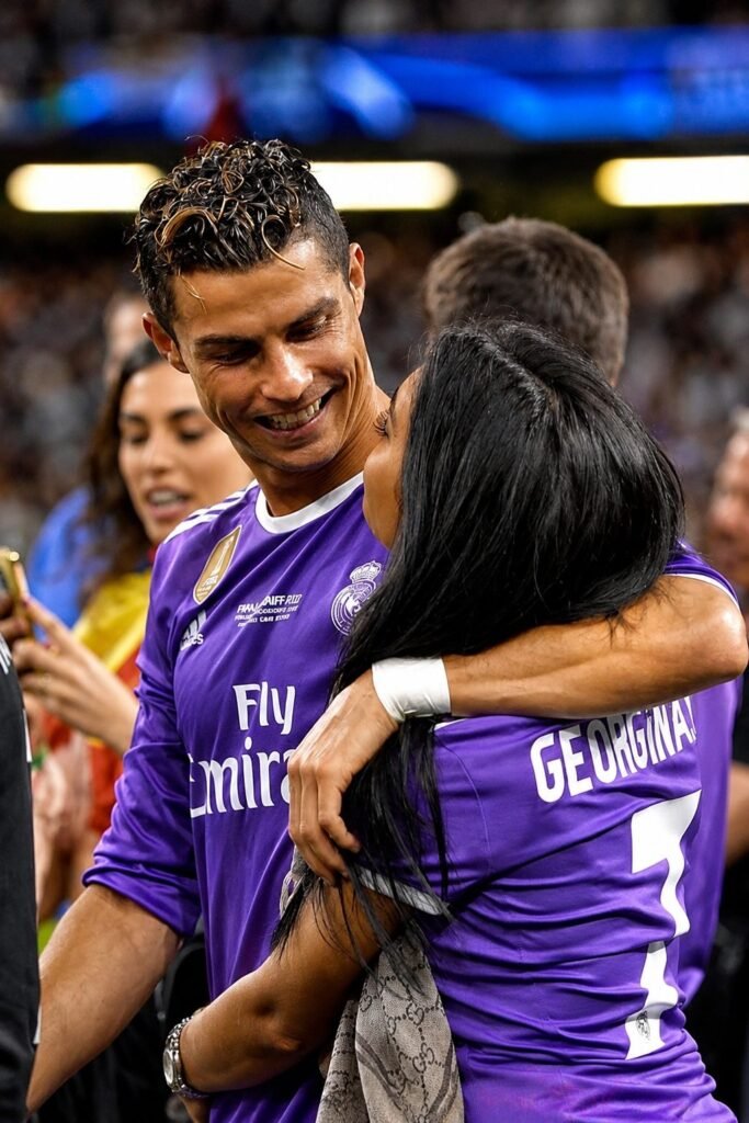 Cristiano Ronaldo, in a purple Real Madrid away shirt, embraces Georgina Rodriguez, who wears a purple shirt printed with the name GEORGINA and the number 7.